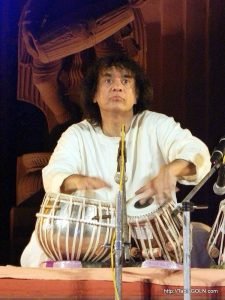 Ustad Zakir Hussain performing at Konark, Odisha. This illustrates the common sitting position used by tabla players.